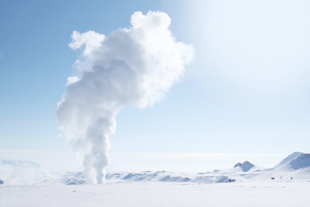 Vapor de gêiser saindo do solo com neve para ser utilizado como energia renovável geotérmica